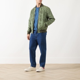 Model wearing Scotch & Soda Reversible Printed Bomber Jacket in Sky Captain, paired with blue T-shirt and navy trousers