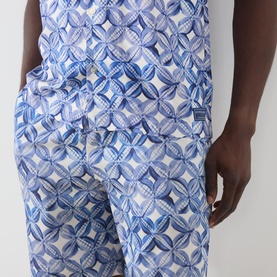 Model wearing Scotch & Soda casual shirt in Tiles Flower print, blue and white geometric floral pattern, relaxed fit with elasticated waist detail.