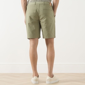 Model wearing Scotch & Soda Oil Green 300 chino shorts, rear view, styled with white trainers