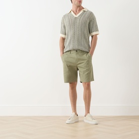 Model wearing Scotch & Soda Oil Green 300 chino shorts, styled with a knit polo shirt and white trainers.