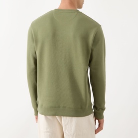 Model wearing Scotch & Soda Seasonal Essentials Logo Badge Sweatshirt in Oil Green, crew neck, ribbed trims, back view, styled with ecru trousers.
