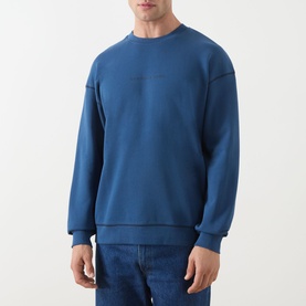 Model wearing Scotch & Soda Ensign Blue crew neck sweatshirt in 100% cotton, styled with blue jeans.