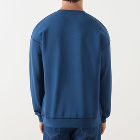 Model wearing Scotch & Soda Ensign Blue crew neck sweatshirt, rear view, styled with blue jeans