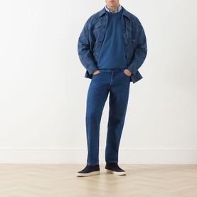Model wearing Scotch & Soda Ensign Blue crew neck sweatshirt with denim jacket, blue jeans and dark canvas shoes.