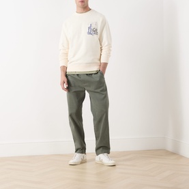 Model wearing Scotch & Soda Work-Out Art Logo Sweatshirt in Eggnog, crew neck, with olive chinos and white trainers.