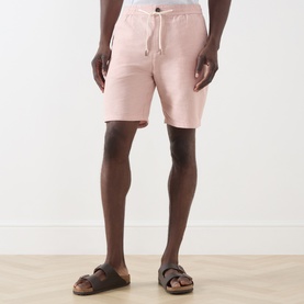 Model wearing Scotch & Soda Fave Bermuda Shorts in Misty Rose, mid-rise with drawstring waist, styled with brown leather sandals