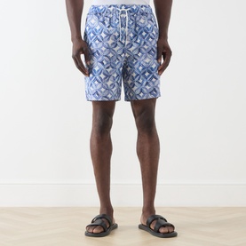 Model wearing Scotch & Soda Tile Flower Printed Bermuda Shorts in blue geometric print, styled with black leather sandals