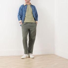 Model wearing Scotch & Soda 3 Crosses Logo T-Shirt in Oil Green 300, styled with khaki trousers, blue overshirt and white trainers.