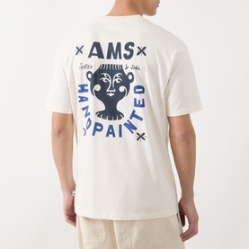 Model wearing Scotch & Soda Artwork Logo T-Shirt in Eggnog, showing back graphic with AMS hand-painted face artwork in navy blue