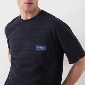 Model wearing Scotch & Soda Logo Texture Jacquard Stripe T-Shirt in Sky Captain with chest pocket and logo patch detail.