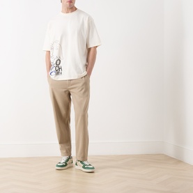 Model wearing Scotch & Soda Work-Out Art Logo T-Shirt in Eggnog with beige chinos and green leather trainers.