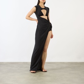 Model wearing Skims Sarong Dress in Onyx, a black maxi dress with cut-out bodice and wrap skirt with thigh-high split, styled with black sandals
