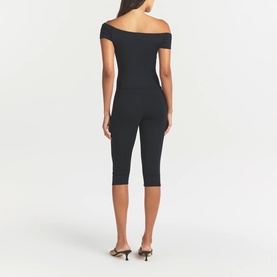 Model wearing Skims Obsidian leggings with matching off-shoulder top, styled with black kitten heel mules, rear view.