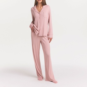 Model wearing Skims Morganite pyjamas with long-sleeve button-up top and wide-leg trousers in soft pink tones