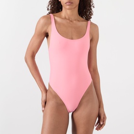 Model wearing pink scoop-neck one-piece swimsuit with low back and high-cut leg, minimal coverage style.