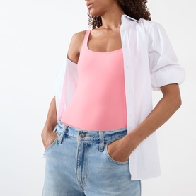 Model wearing pink sleeveless scoop-neck camisole, styled with white open shirt and light blue denim jeans