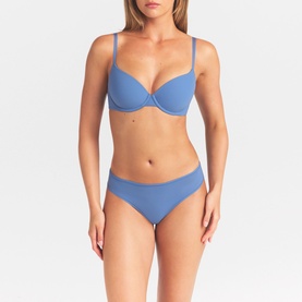Model wearing Skims Arctic thong with matching blue bra, smooth minimal design in mid-blue fabric