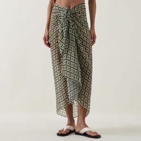 Model wearing Away That Day Navy/Gold Link Print Sarong, styled with white flat sandals, draped wrap silhouette with ruched knot detail