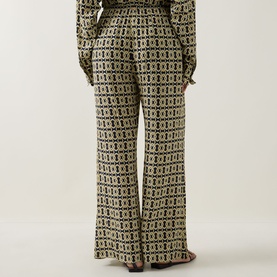 Model wearing Away That Day Navy/Gold Link Print trousers in wide-leg silhouette, styled with matching printed top, rear view.
