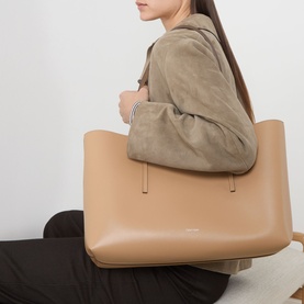 Model carrying Calvin Klein tannin tote bag with silver-tone hardware, styled with a taupe suede jacket