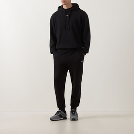 Model wearing Hugo black cotton hoodie with matching black joggers and grey trainers