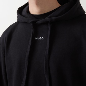 Model wearing Hugo black cotton hoodie with small white logo print at centre chest and drawstring hood.