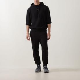 Model wearing Hugo black cotton hoodie with short sleeves, styled with matching black joggers and grey trainers