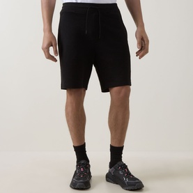 Model wearing Hugo black cotton shorts with drawstring waist, styled with black trainers and socks