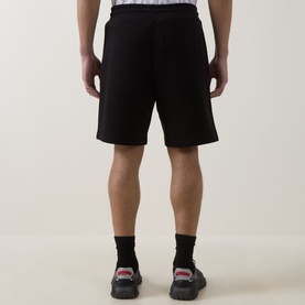 Model wearing Hugo black cotton shorts with drawstring waist, styled with black socks and chunky trainers, rear view