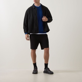 Model wearing Hugo black cotton shorts, styled with black zip-up jacket, blue sweatshirt and black trainers.