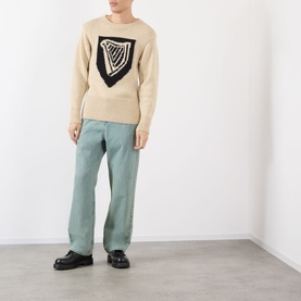Model wearing JW Anderson Harp Knitted Sweater in ivory with navy harp motif, styled with sage wide-leg trousers and black loafers.