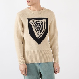 Model wearing JW Anderson Harp Knitted Sweater in ivory wool with navy harp intarsia motif, crew neck and ribbed trims, styled with sage green
