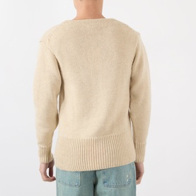 Model wearing JW Anderson Harp Knitted Sweater in ivory wool, rear view, ribbed trims and straight hemline visible, styled with blue jeans.