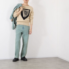 Model wearing JW Anderson Harp Knitted Sweater in ivory with black harp motif, styled with sage green trousers and black loafers.