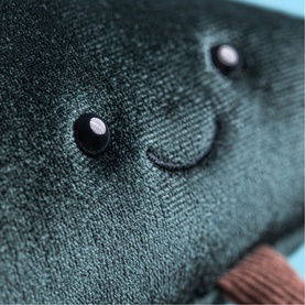 Jellycat plush soft toy close-up showing embroidered smiley face with bead eyes on dark teal knitted fabric