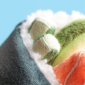 Jellycat plush sushi roll toy close-up showing textured green, orange and white fabric layers in multi-colour soft toy detail