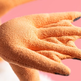 Jellycat plush toy close-up showing textured orange terry-cloth hand detail against pink background