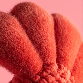 Jellycat plush toy close-up showing soft red textured fabric with ribbed and fluffy sections in coral-red tones