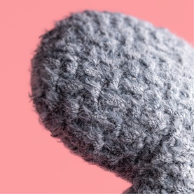 Jellycat grey textured plush soft toy, close-up detail showing fluffy knitted-style fabric texture against pink background