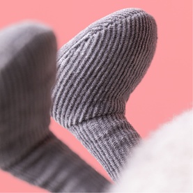 Jellycat plush soft toy close-up detail showing grey ribbed corduroy paw against a pink background