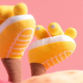 Jellycat plush soft toy close-up showing yellow and white textured feet with small embellished toe details on pink background