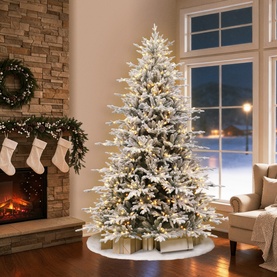 Puleo Pre-lit Flocked Arcadia Artificial Christmas Tree 7.5ft with warm white LED lights, styled in a cosy living room with fireplace