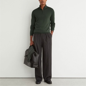 Model wearing Reiss dark green half-zip knit jumper, styled with charcoal wide-leg trousers, carrying a dark grey holdall bag.