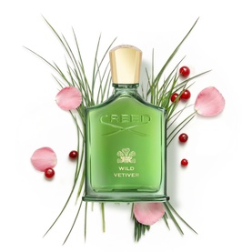 CREED Wild Vetiver Eau De Parfum 100ml in green glass bottle, styled with pink petals, red berries and green grass stems