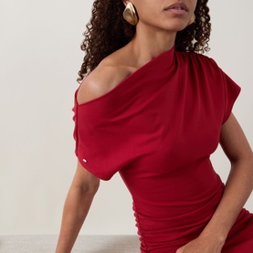 Model wearing Ted Baker Maevely Asymmetric Flared Dress in red, with asymmetric one-shoulder neckline and short ruched sleeve, styled with gold