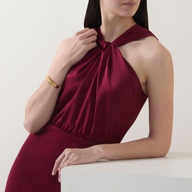 Model wearing Ted Baker Mellana Twist-Detail Dress in Burnt Red, satin halter neckline with twist detail, styled with a gold bangle bracelet.