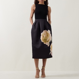 Model wearing Ted Baker Verinie Placement Floral Dress in black, sleeveless midi with large floral print skirt, styled with nude heeled sandals
