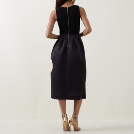 Model wearing Ted Baker Verinie Placement Floral Dress in black, midi length with pleated satin skirt, rear zip; styled with gold heeled sandals.