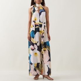 Model wearing Ted Baker Camea Floral Print Jumpsuit in Navy with large floral print, halter neckline, tie detail and wide-leg silhouette