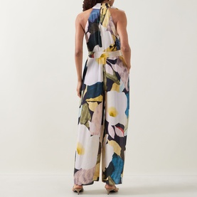 Model wearing Ted Baker Camea Floral Print Jumpsuit in Navy, showing rear halter neck, tie detail, wide-leg silhouette with large floral print.